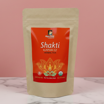 Shakti Kapha EZ Herbal Tea package on a marble surface with a pink background