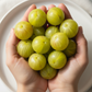 Hands holding a bunch of organic amalaki on a white plate