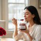 Woman eating Organic Gulkand with a spoon in a bright room with flowers on the table.