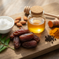 Glass jar of honey, dates, turmeric, and other ingredients on a wooden board.