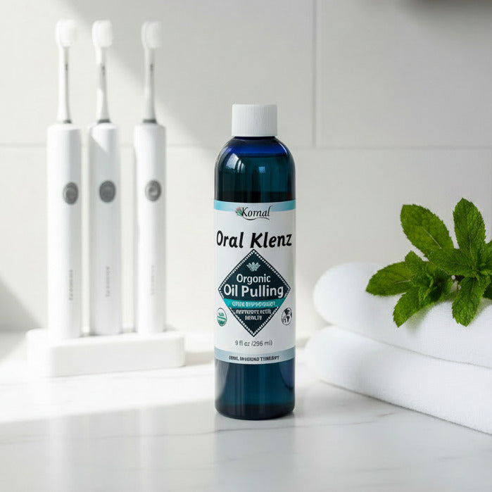 Bottle of Oral Klenz Organic Oil Pulling with Peppermint on a white countertop with mint and tooth brushes
