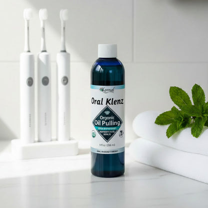 Bottle of Oral Klenz Organic Oil Pulling with Peppermint on a white countertop with mint and tooth brushes
