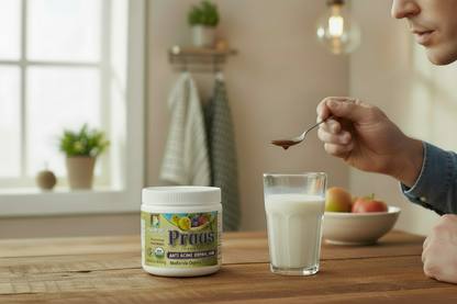Person holding a spoon with a Organic Praas herbal jam over a glass of milk on a wooden table.