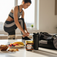 Woman preparing for a workout with healthy snacks and a gym bag on a kitchen counter.