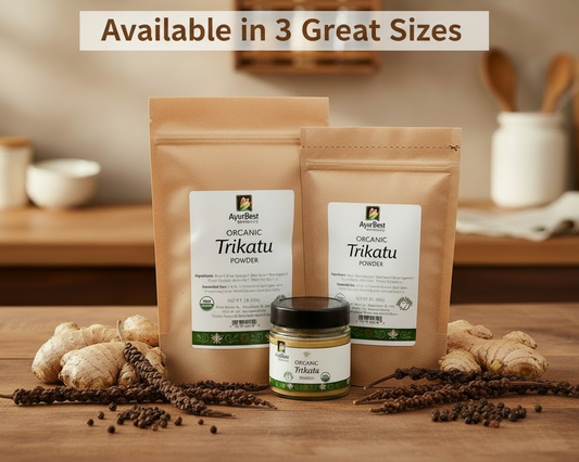 Two packages of AyurBest Organic Trikatu powder on a wooden surface with spices and a blurred kitchen background.