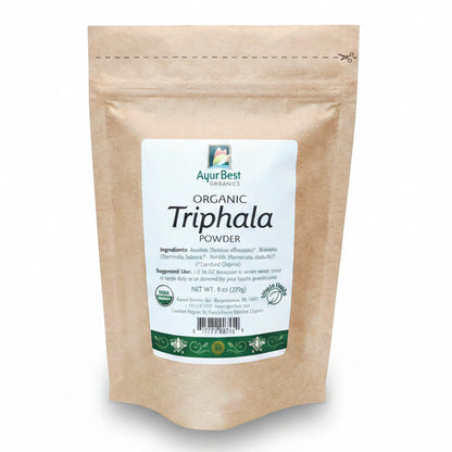 A bag of AyurBest Organic Triphala Powder, with a beige packaging and a green and white label featuring the product name and organic certification symbol.